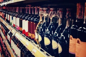 inquadratura laterale di bottiglie di vino su una scaffalatura tipica di enoteca