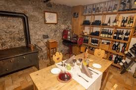 tavolo in apparecchiato per due con cibo e 2 bicchieri di vino rosso sullo sfondo uno scaffale pieno di bottiglie di vino